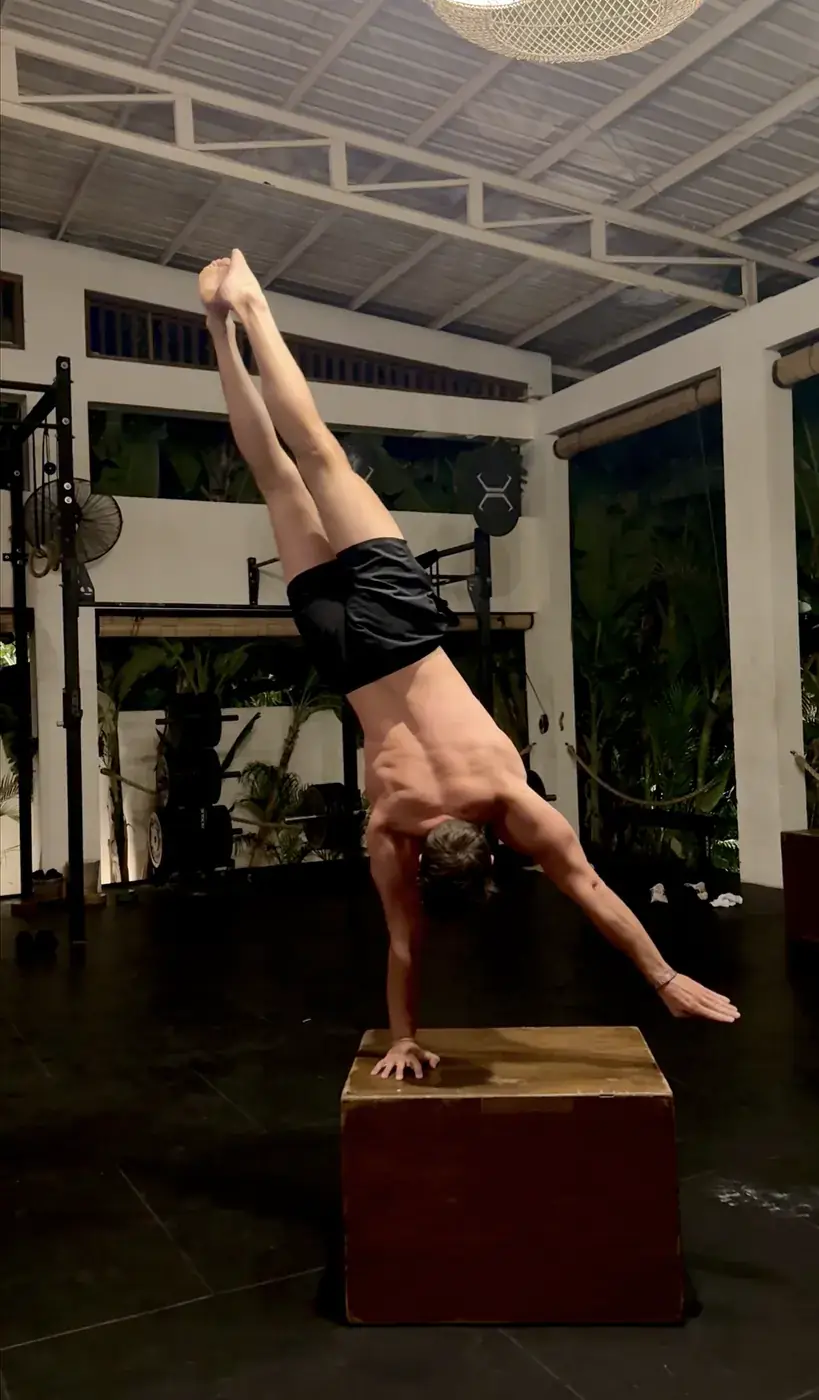 Romain performing a one-arm handstand on a wooden box